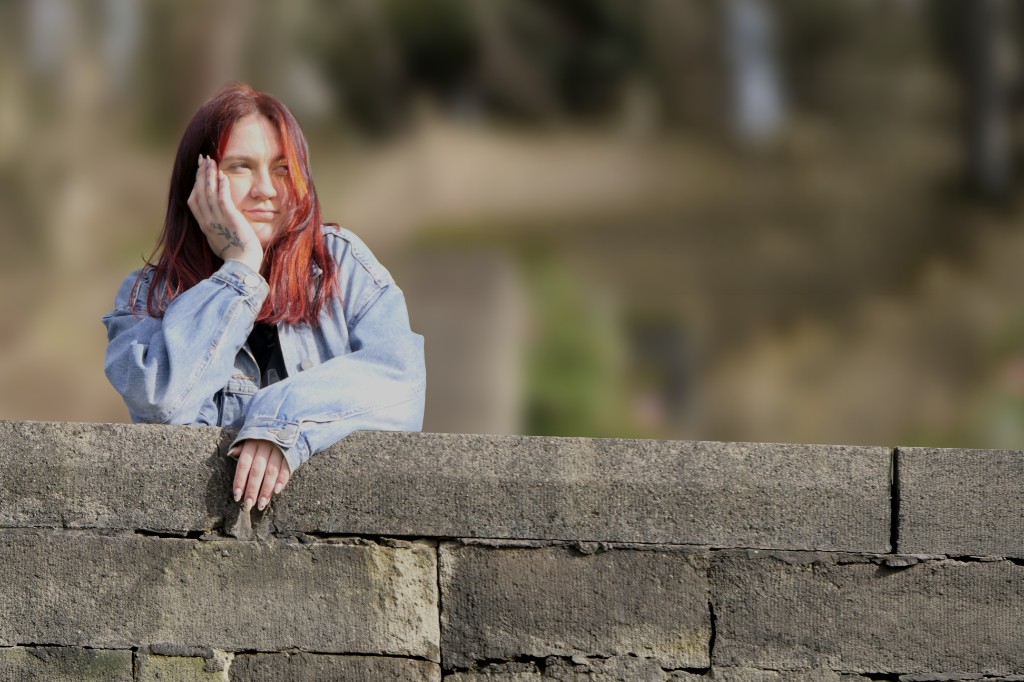 Gracie Alice leaning on a stone wall in sunlight